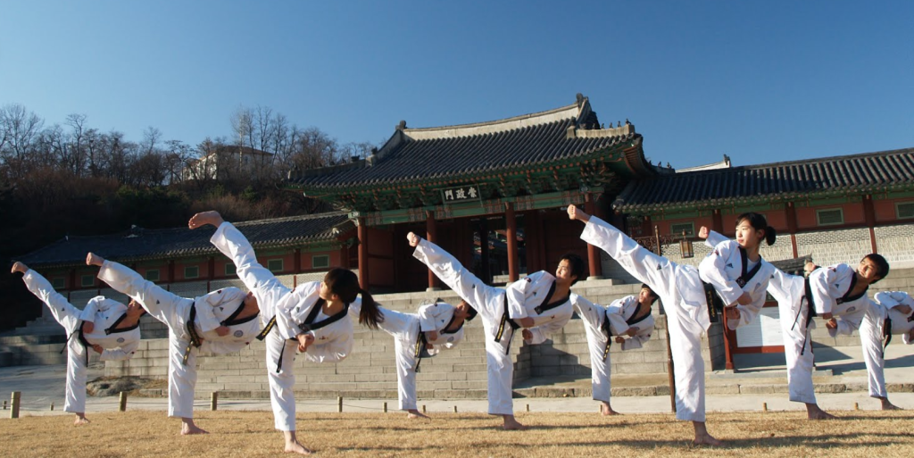 Athlètes performant une suite de Taekwondo devant un bâtiment traditionnel coréen