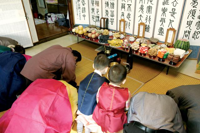 Famille s'inclinant devant une table de Charye pendant Chuseok